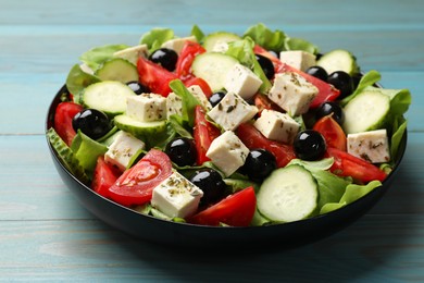 Delicious salad with feta cheese on light blue wooden table, closeup