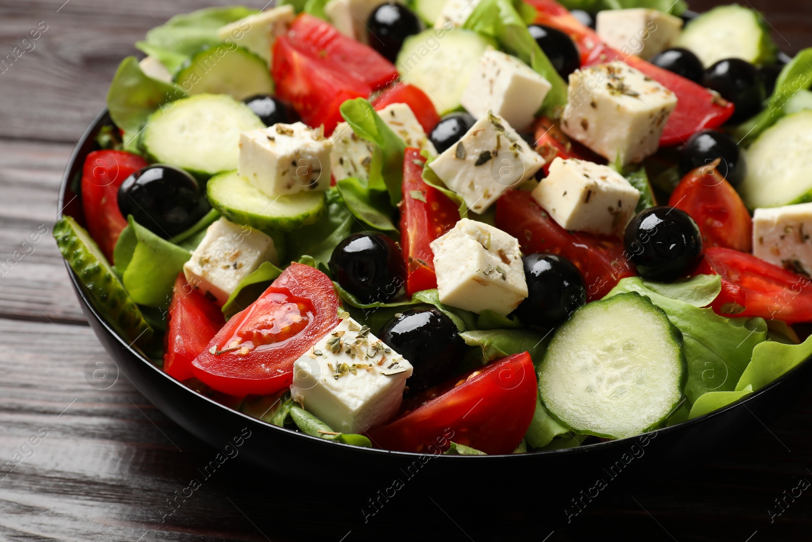 Photo of Delicious salad with feta cheese on wooden table, closeup