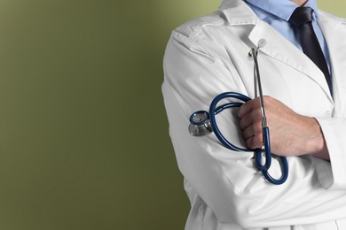 Photo of Doctor with stethoscope on olive background, closeup. Space for text