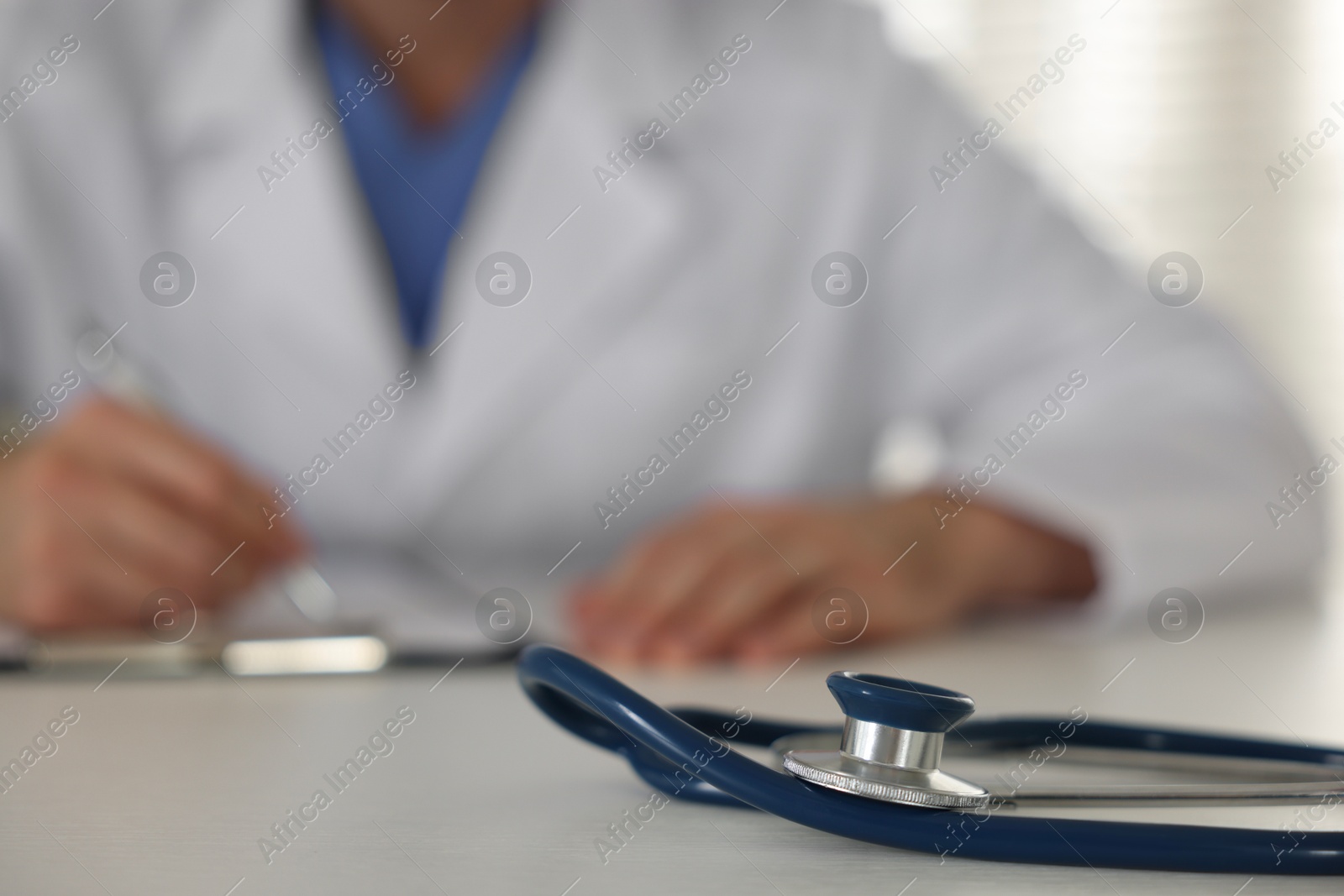 Photo of Doctor working at table, focus on stethoscope