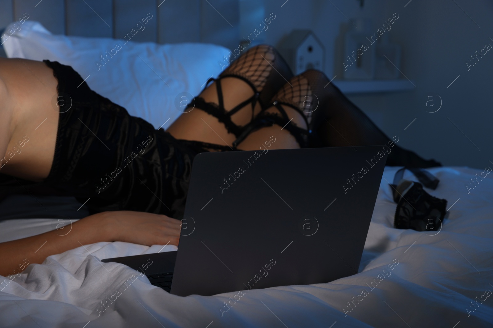 Photo of Prostitution. Webcam model streaming with laptop on bed, closeup