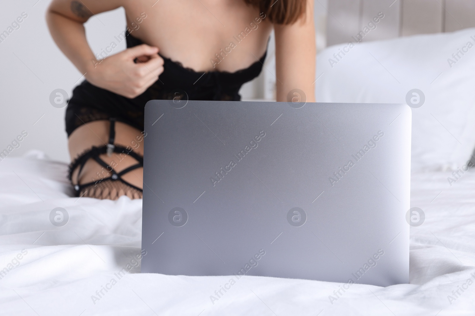 Photo of Prostitution. Webcam model streaming with laptop on bed, closeup