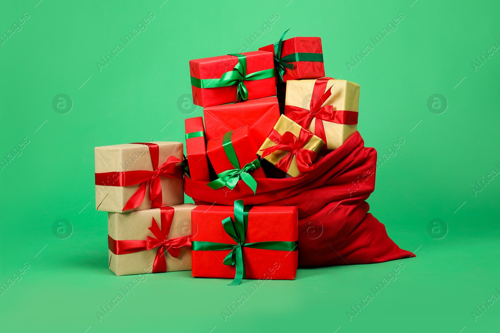 Photo of Red Santa Claus bag with gift boxes on green background