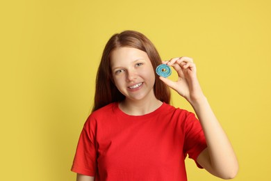 Photo of Happy teenage girl holding tasty gummy candy on yellow background