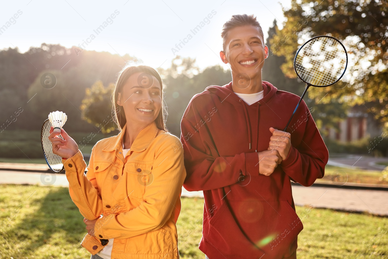 Photo of Young man and woman with badminton rackets and shuttlecock in park on sunny day