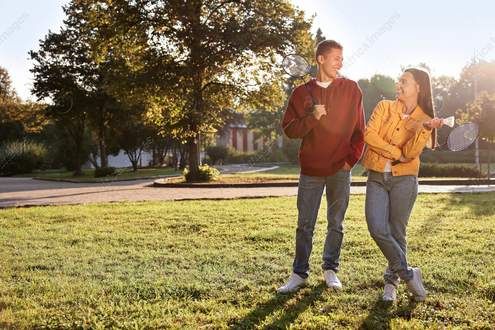 Photo of Young man and woman with badminton rackets and shuttlecock in park on sunny day