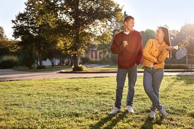 Photo of Young man and woman with badminton rackets and shuttlecock in park on sunny day