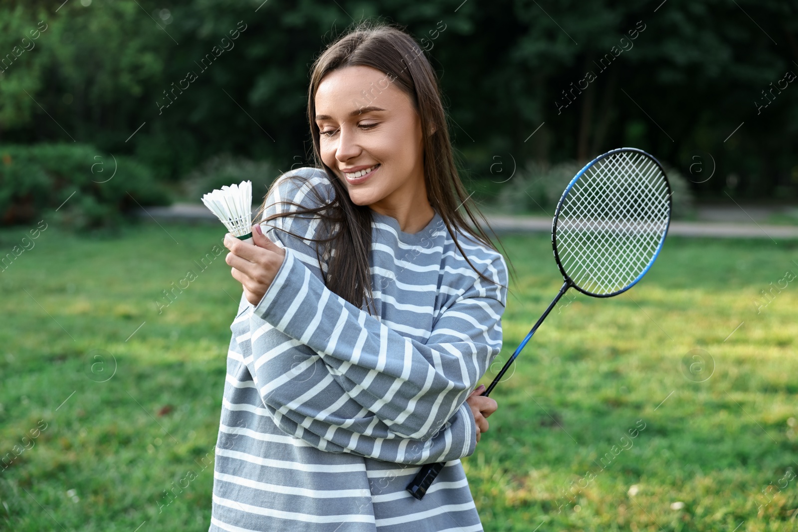 Photo of Happy young woman with badminton racket and shuttlecock in park