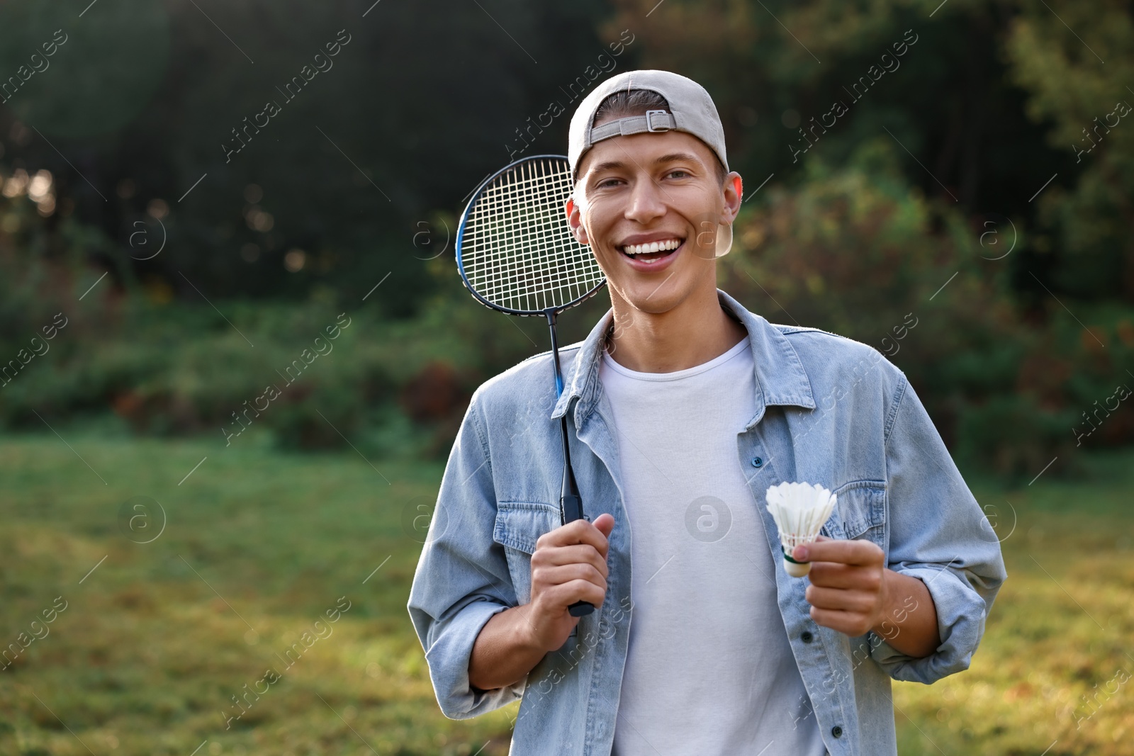 Photo of Happy young man with badminton racket and shuttlecock in park