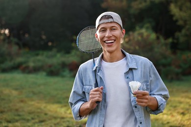 Photo of Happy young man with badminton racket and shuttlecock in park