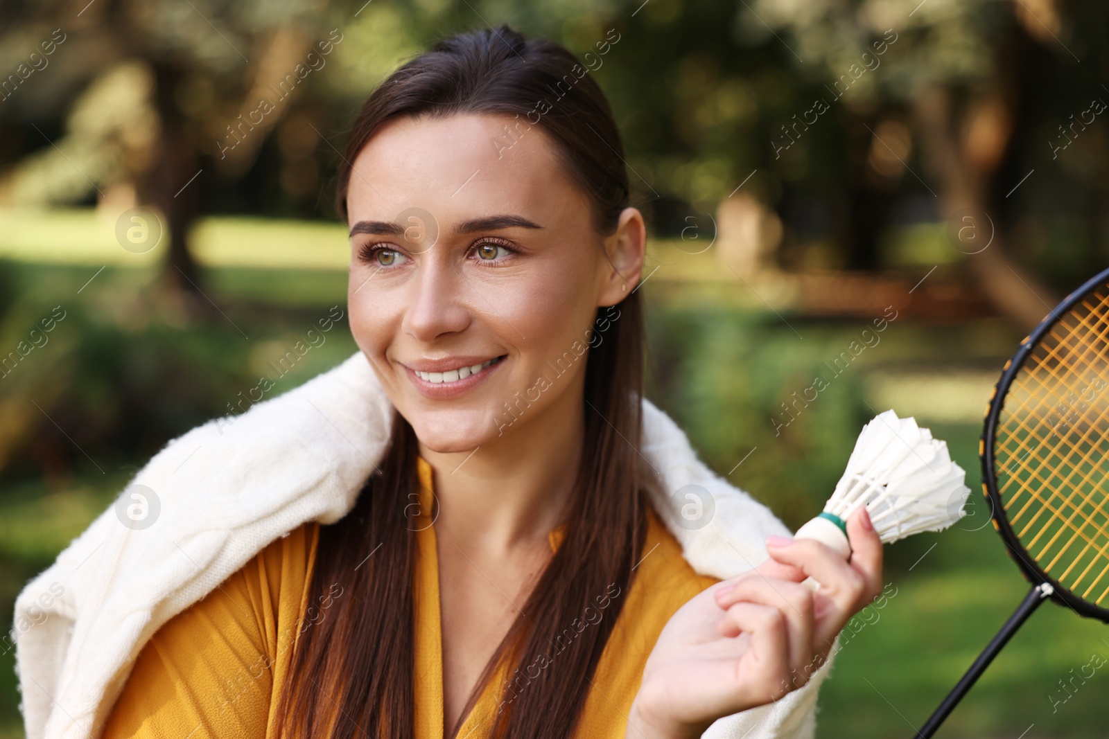 Photo of Happy young woman with badminton racket and shuttlecock in park