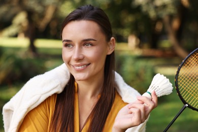 Photo of Happy young woman with badminton racket and shuttlecock in park