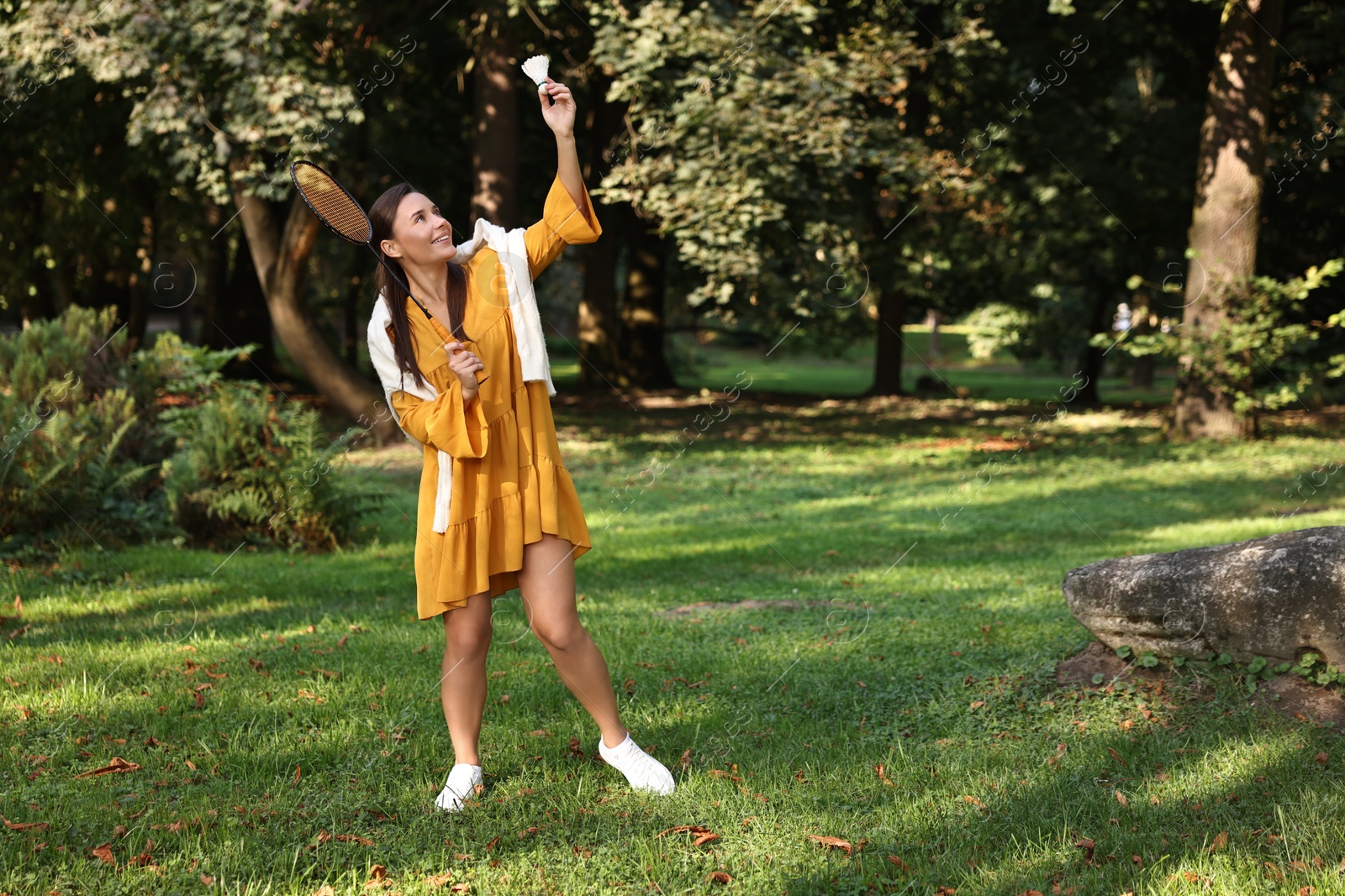 Photo of Happy young woman playing badminton racket in park