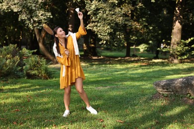 Happy young woman playing badminton racket in park