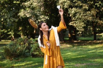 Happy young woman playing badminton racket in park