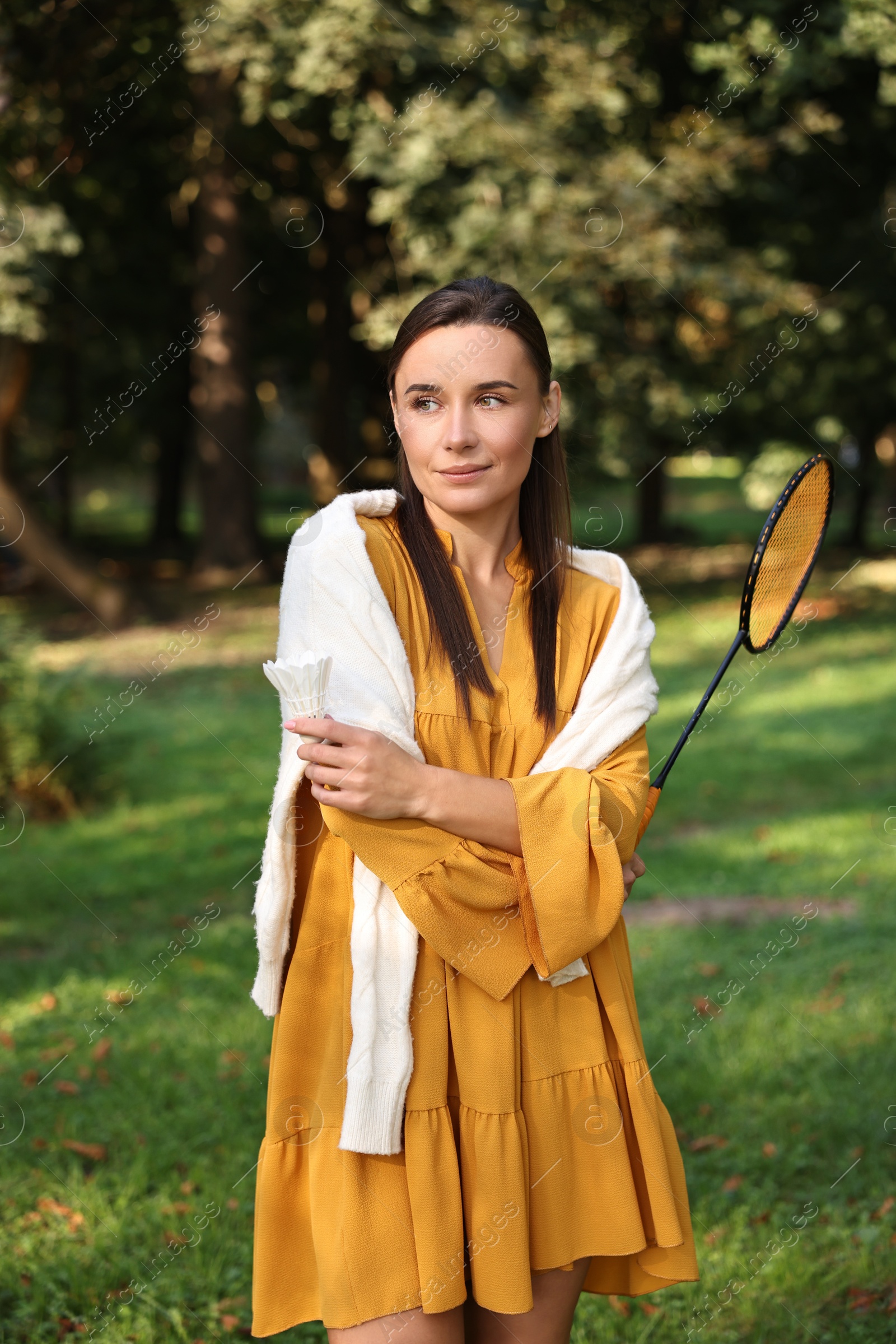 Photo of Young woman with badminton racket and shuttlecock in park