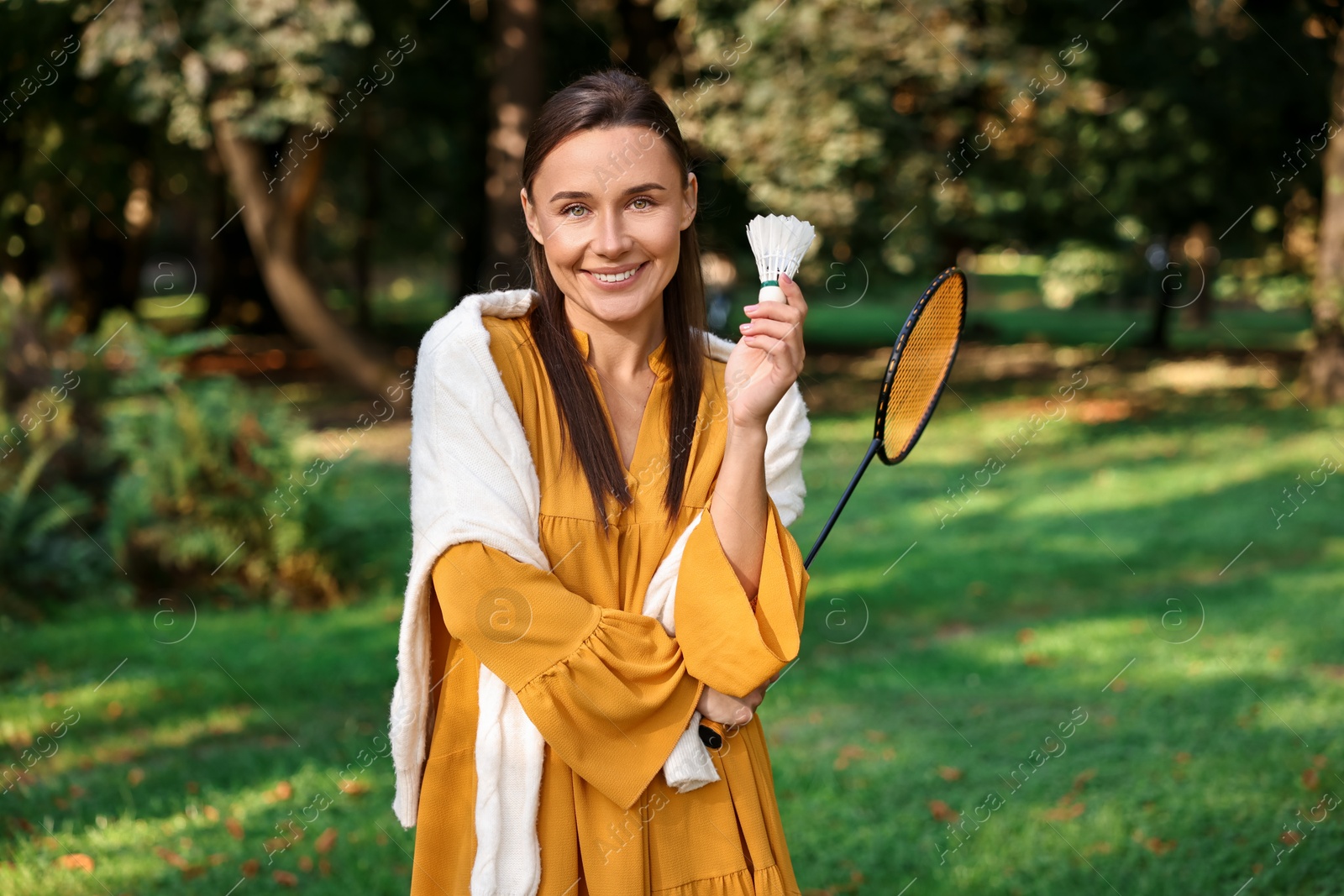 Photo of Happy young woman with badminton racket and shuttlecock in park