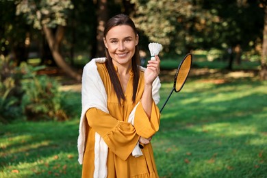 Photo of Happy young woman with badminton racket and shuttlecock in park