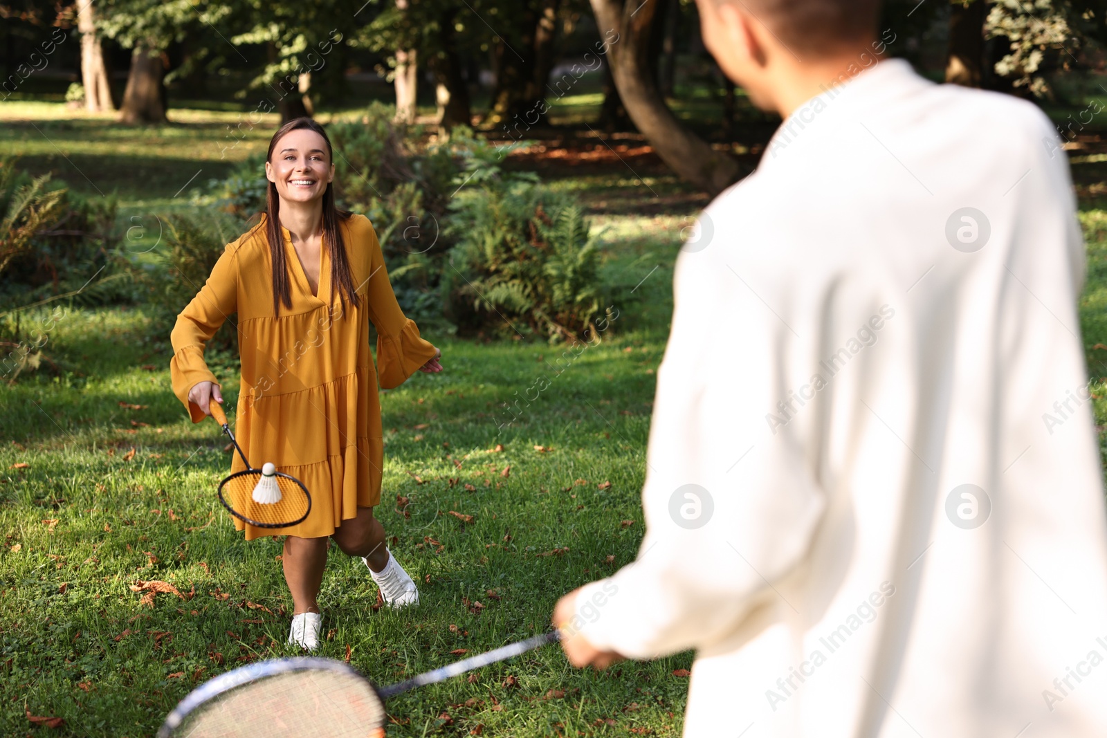 Photo of Young woman and man playing badminton in park, selective focus