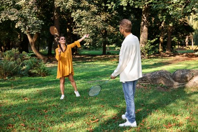 Photo of Young woman and man playing badminton in park, selective focus