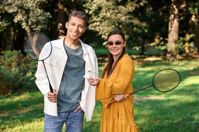 Photo of Young man and woman with badminton rackets and shuttlecock in park