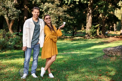 Young man and woman with badminton rackets and shuttlecock in park