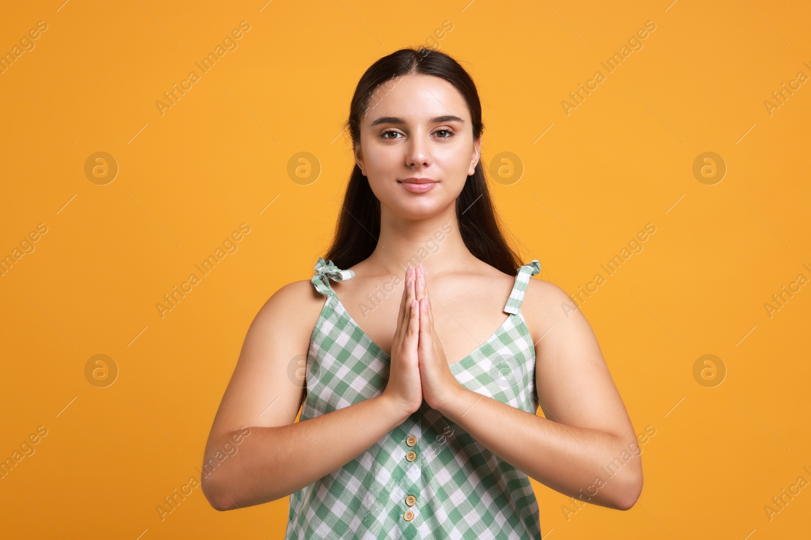 Photo of Young student praying for good exam result on orange background