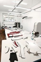 Photo of Professional workshop with different fabrics, white table and tools