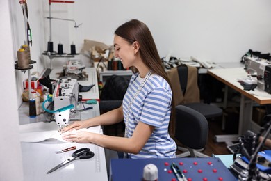 Young woman working with sewing machine in professional workshop