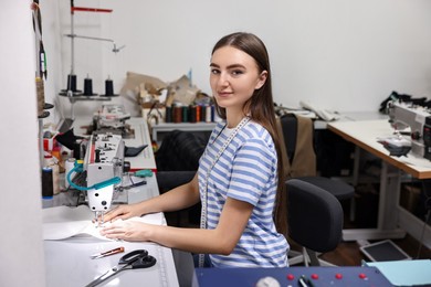 Young woman working with sewing machine in professional workshop