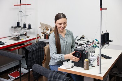 Photo of Young woman working with sewing machine in professional workshop