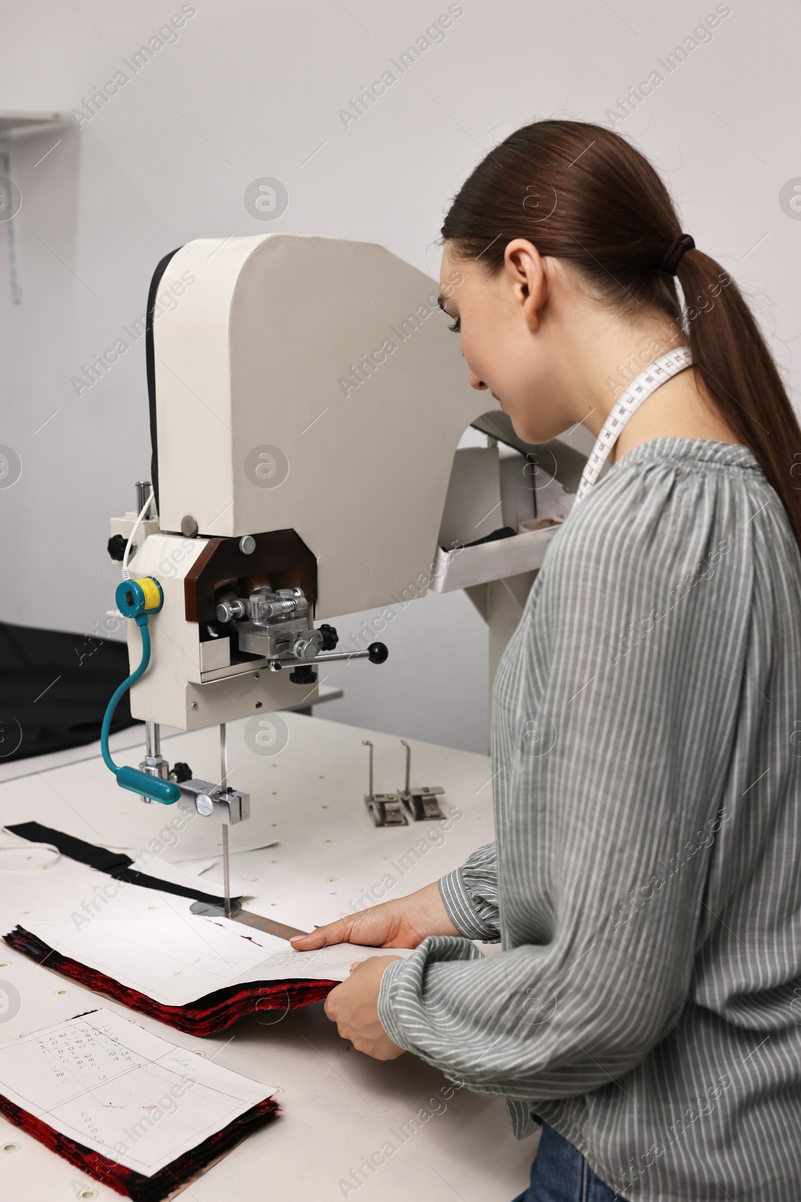 Photo of Young woman working at white table in professional workshop