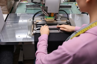 Young woman working with machine in professional workshop, closeup