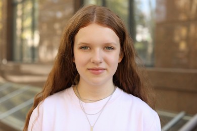 Portrait of happy teenage girl with long hair outdoors