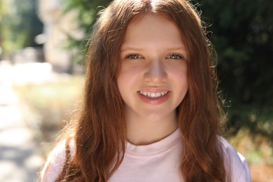 Photo of Portrait of happy teenage girl with long hair outdoors