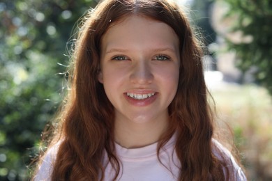 Portrait of happy teenage girl with long hair outdoors