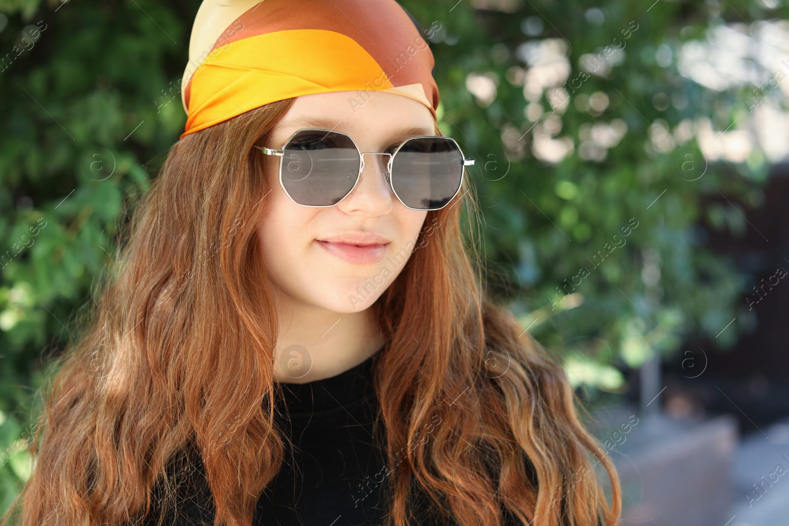 Photo of Portrait of happy teenage girl with long hair wearing sunglasses and bandana outdoors