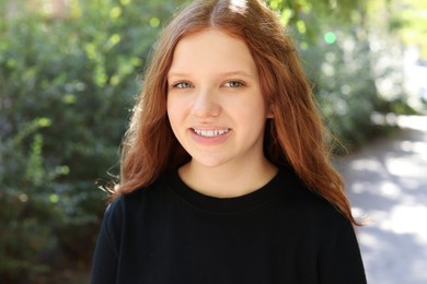 Portrait of happy teenage girl with long hair outdoors