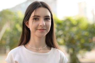 Photo of Portrait of beautiful teenage girl on city street. Space for text