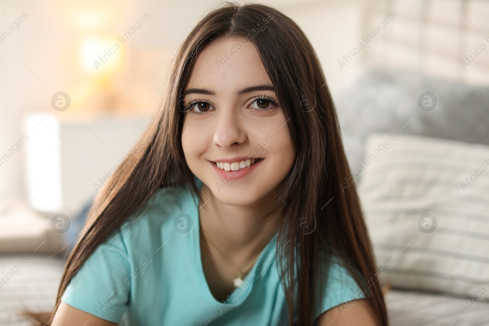 Photo of Portrait of smiling teenage girl on bed at home