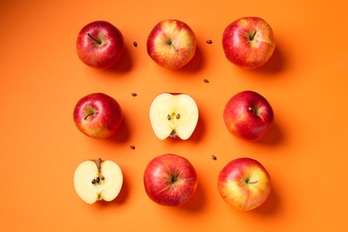 Fresh red apples and seeds on orange background, flat lay