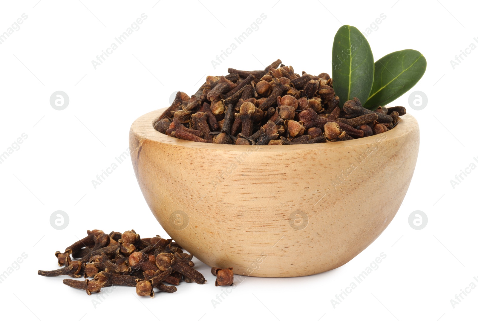 Photo of Dry clove buds and green leaves in wooden bowl on white background. Aromatic spice