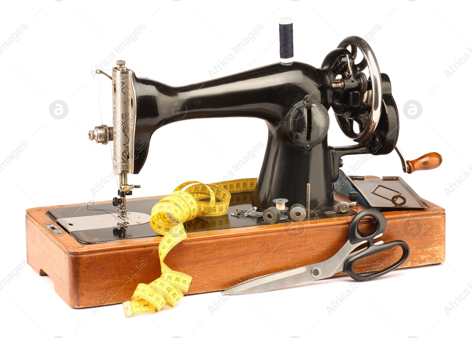 Photo of Sewing machine with measuring tape, scissors and spools of threads isolated on white