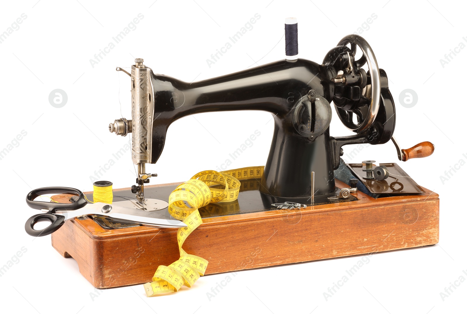 Photo of Sewing machine, measuring tape, scissors, safety pins and spools of threads isolated on white