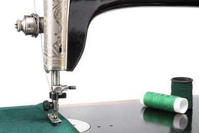 Photo of Sewing machine with green fabric and spools of threads isolated on white