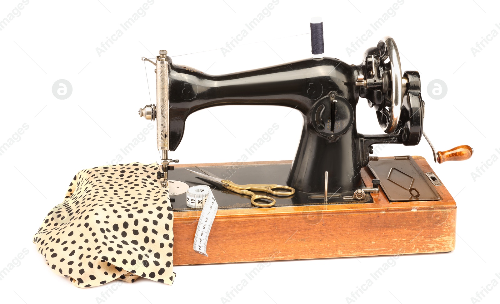 Photo of Sewing machine with fabric, measuring tape, scissors and spool of thread isolated on white