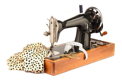 Photo of Sewing machine with fabric, measuring tape, scissors and spool of thread isolated on white