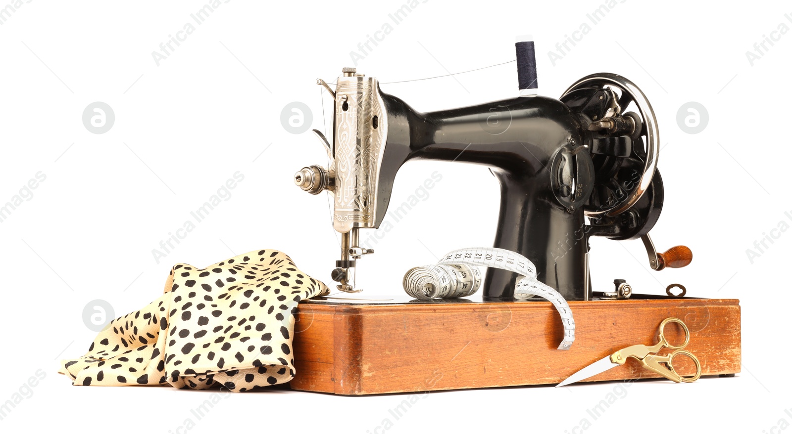 Photo of Sewing machine with fabric, measuring tape, scissors and spool of thread isolated on white