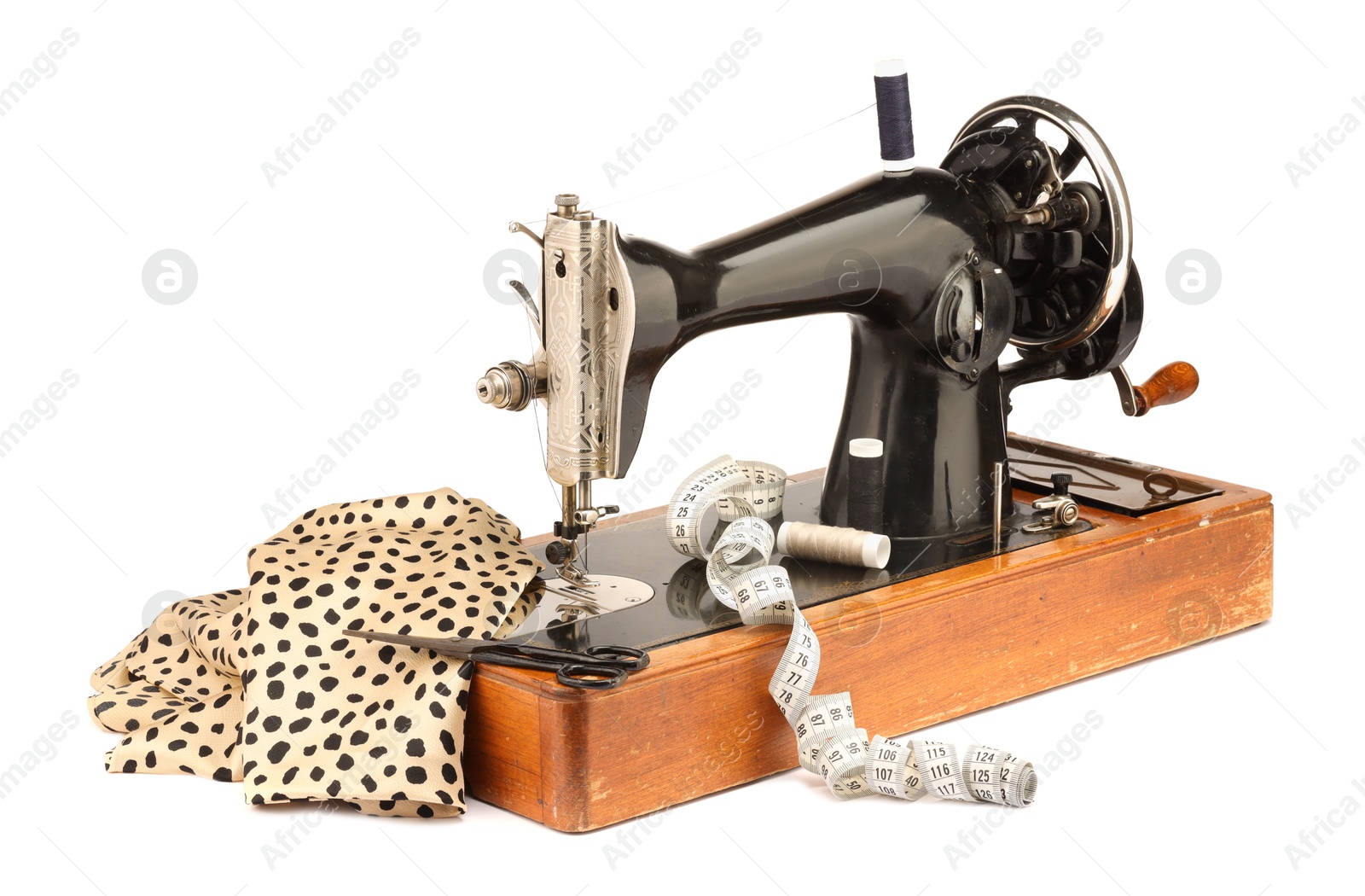 Photo of Sewing machine with fabric, measuring tape, scissors and spools of threads isolated on white