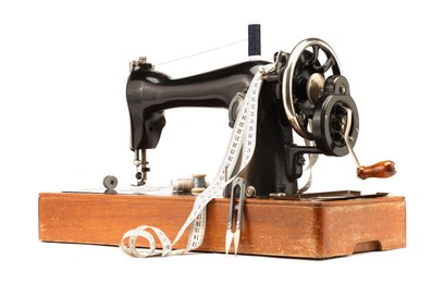 Photo of Sewing machine, measuring tape, cutter and spools of threads isolated on white